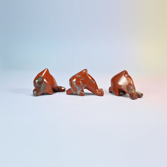 Three red jasper dolphin crystal carvings, brick red natural stone with light veins