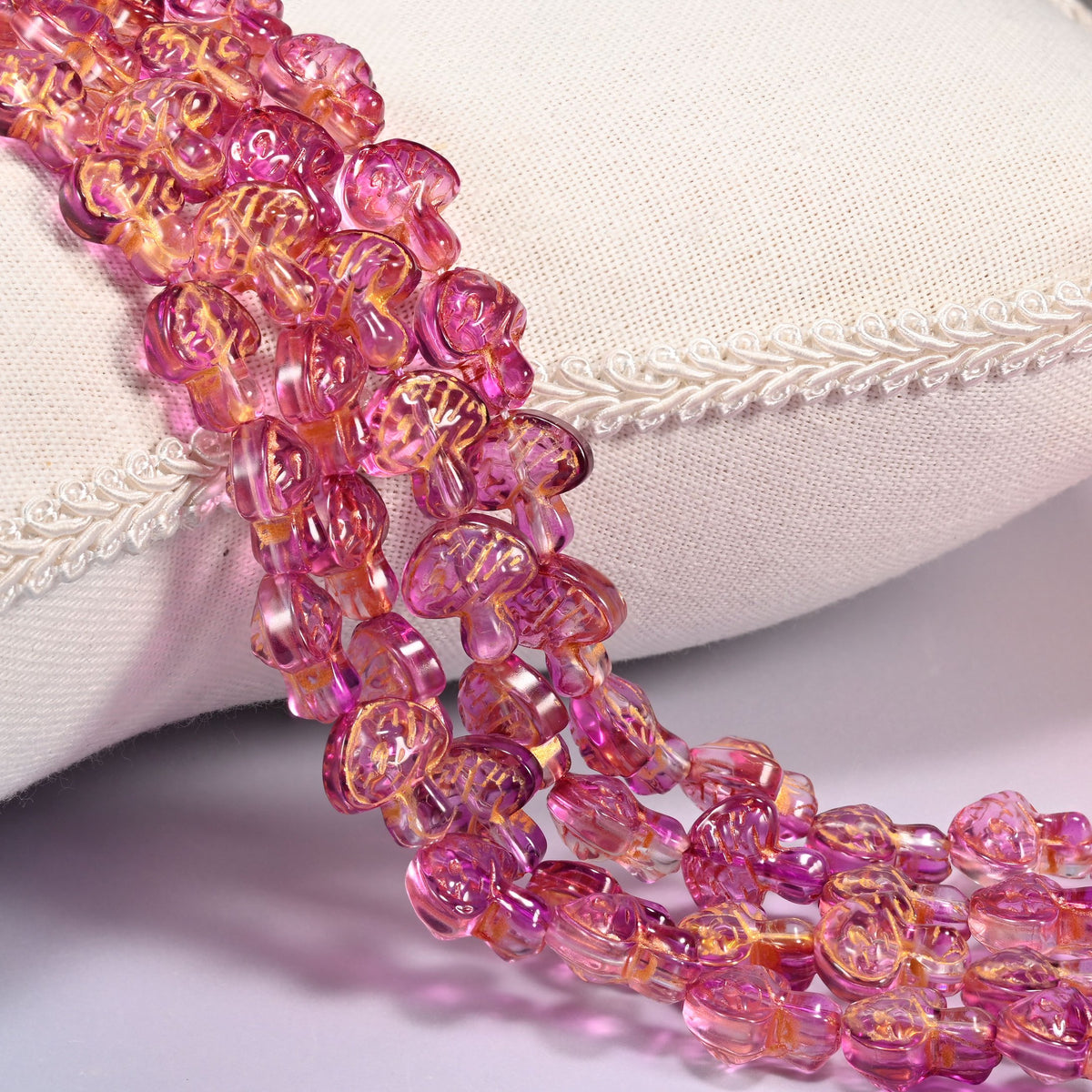 Pink gold flat mushroom glass beads, 13x12mm pressed glass, several strands draped forward in rows.