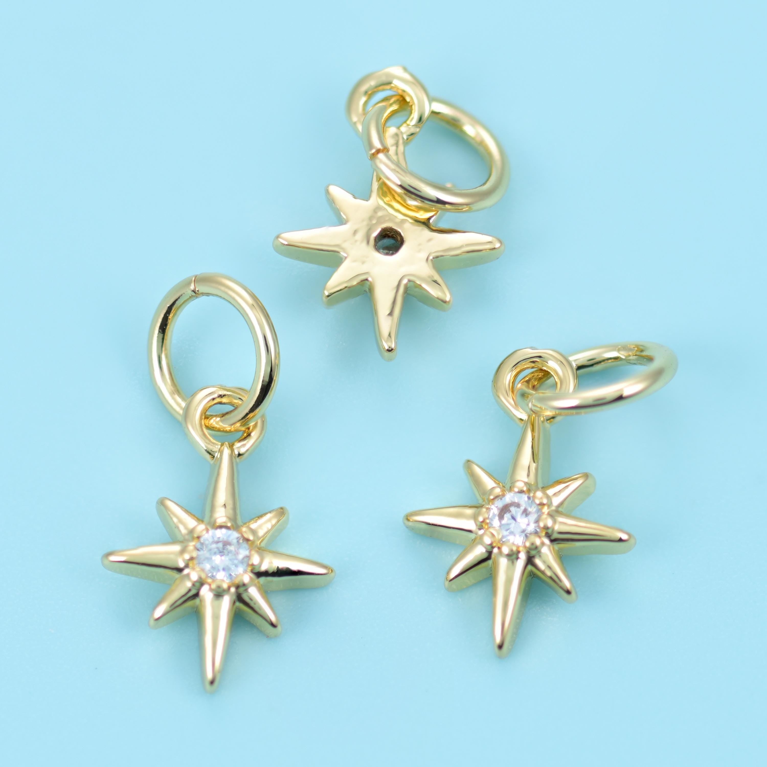 A slim eight-point star with long tapered rays and a bright round zircon set at the centre, finished in warm polished gold…