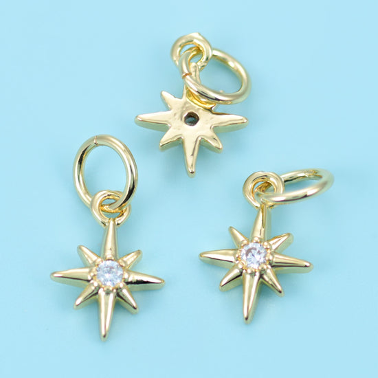A slim eight-point star with long tapered rays and a bright round zircon set at the centre, finished in warm polished gold…