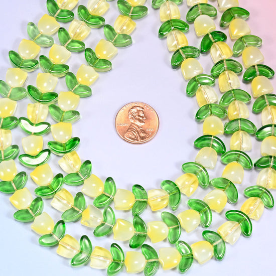 Wide view of a circular coil of yellow tulip and green leaf glass beads on a lavender background, showing the alternating pattern.