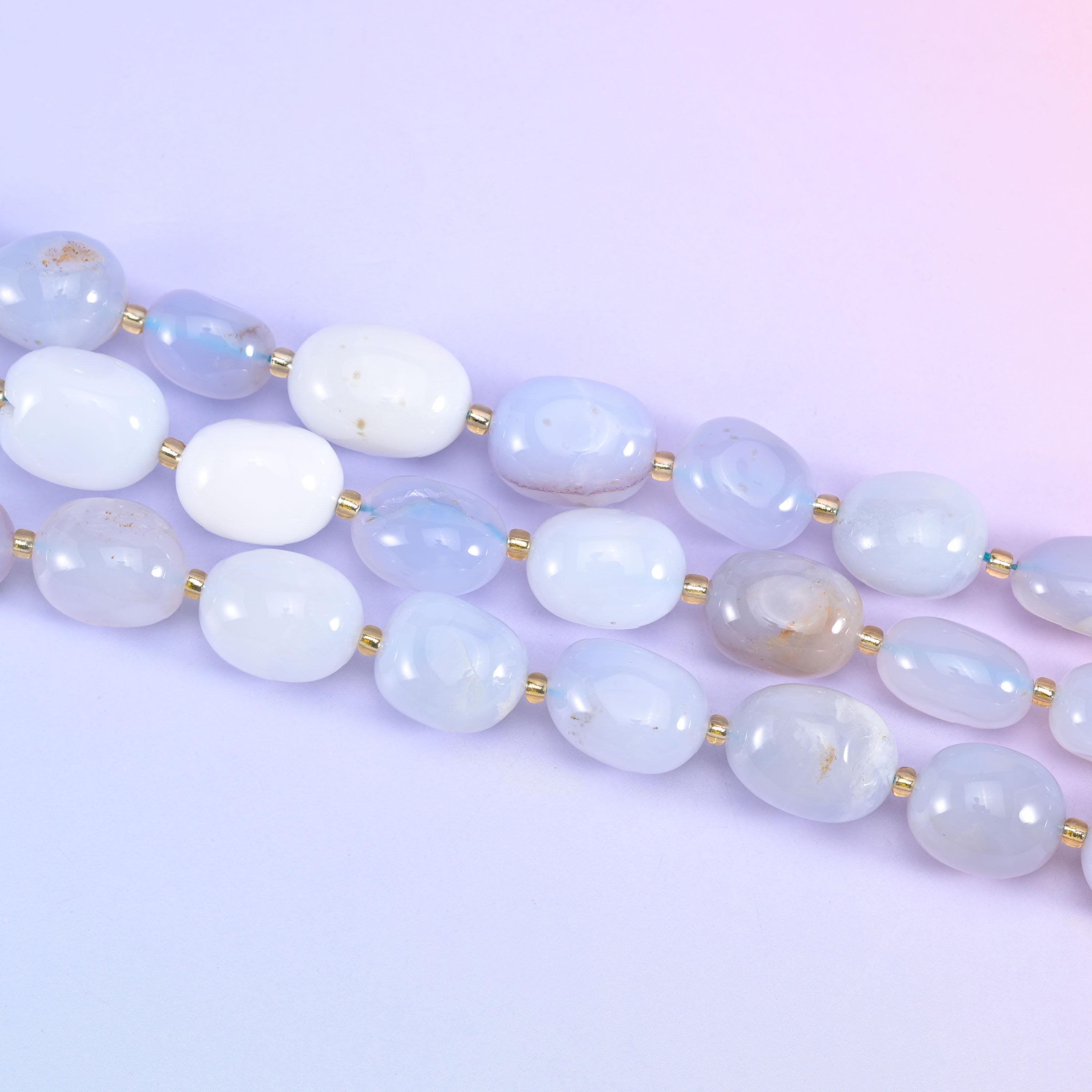Two strands of 10-17mm chalcedony nuggets running diagonally across a pale lilac backdrop