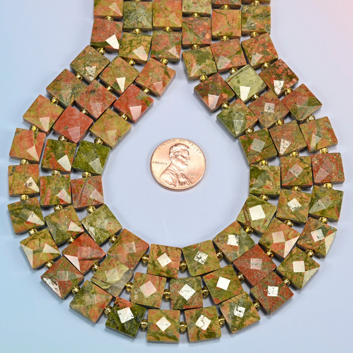 Natural unakite faceted flat square strands formed into a teardrop loop around a US penny for scale