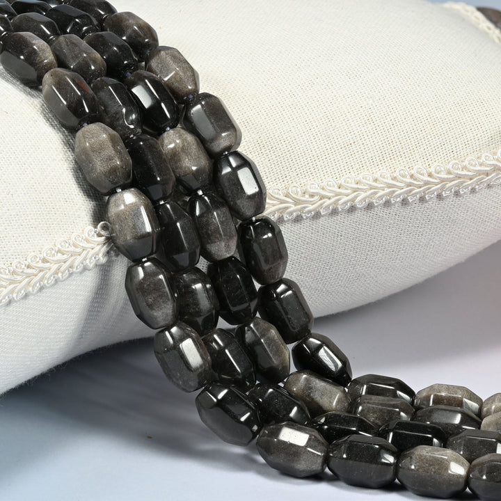 Silver Obsidian faceted barrel drum beads draped in a soft curve, a soft silver sheen rolling across the gray black faces