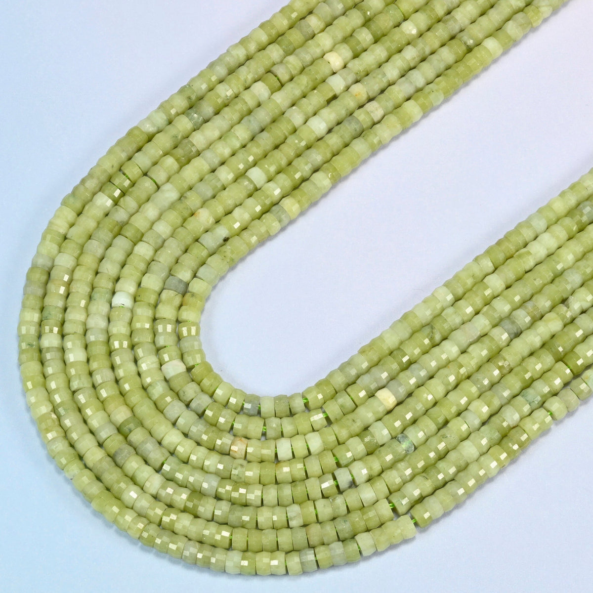 South Jade faceted heishi disc beads in several strands curved into a wide U, light yellow-green stone