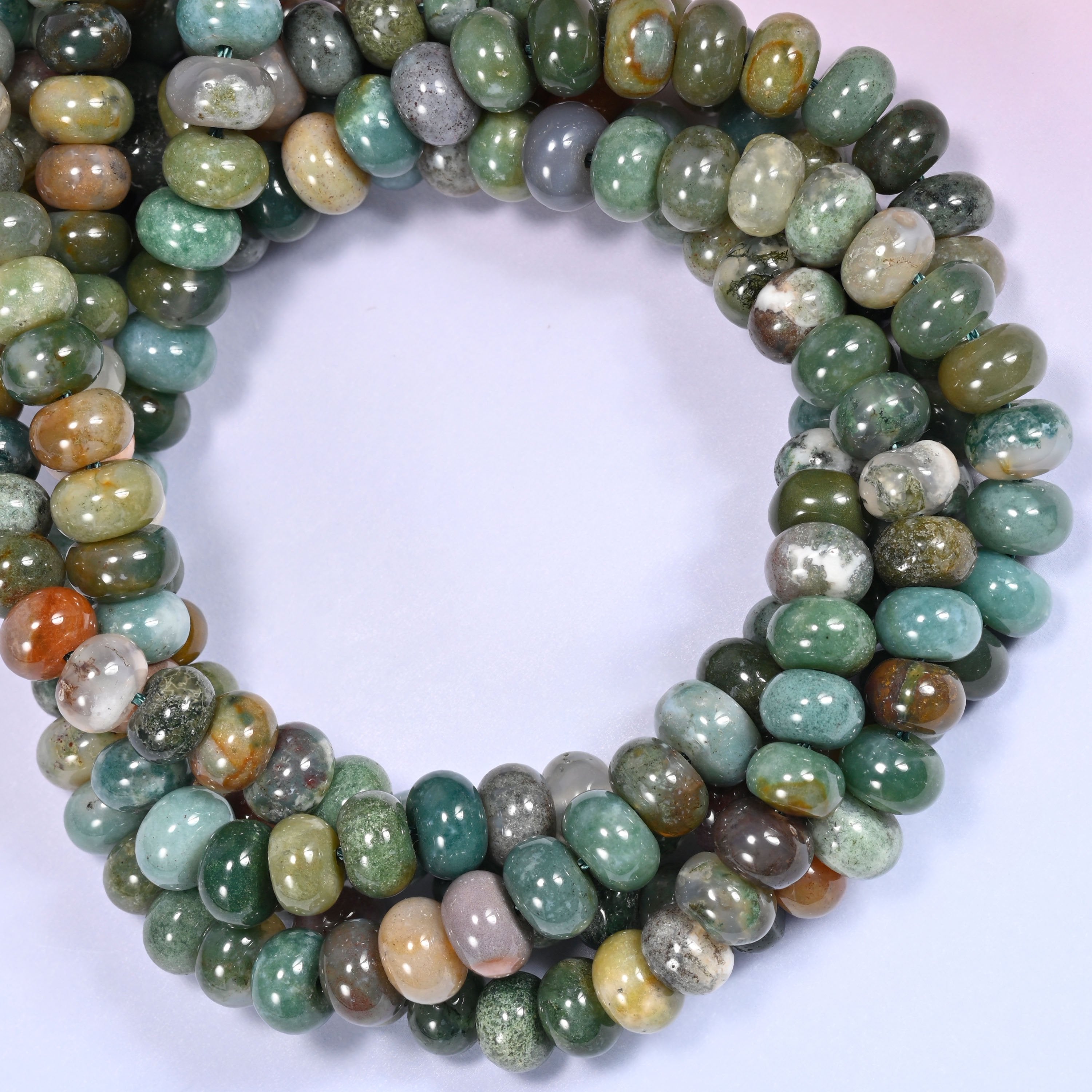 Close-up horizontal row of Indian Agate beads showing the green and orange stone pattern.
