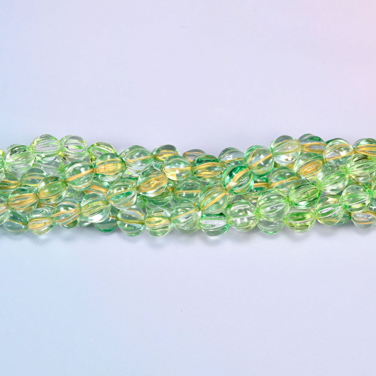Green gold pumpkin glass beads coiled into a ring, shown with a US penny in the open center for scale.