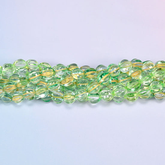 Green gold pumpkin glass beads coiled into a ring, shown with a US penny in the open center for scale.