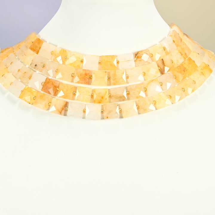 Natural golden healer quartz faceted flat square strands arranged as a layered collar on a white display bust, golden yellow beads across the neck