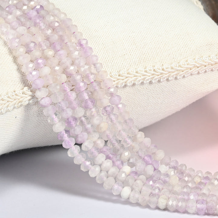 Purple Jade gemstone rondelle beads 4x6mm faceted, strand draped over a cream fabric cushion