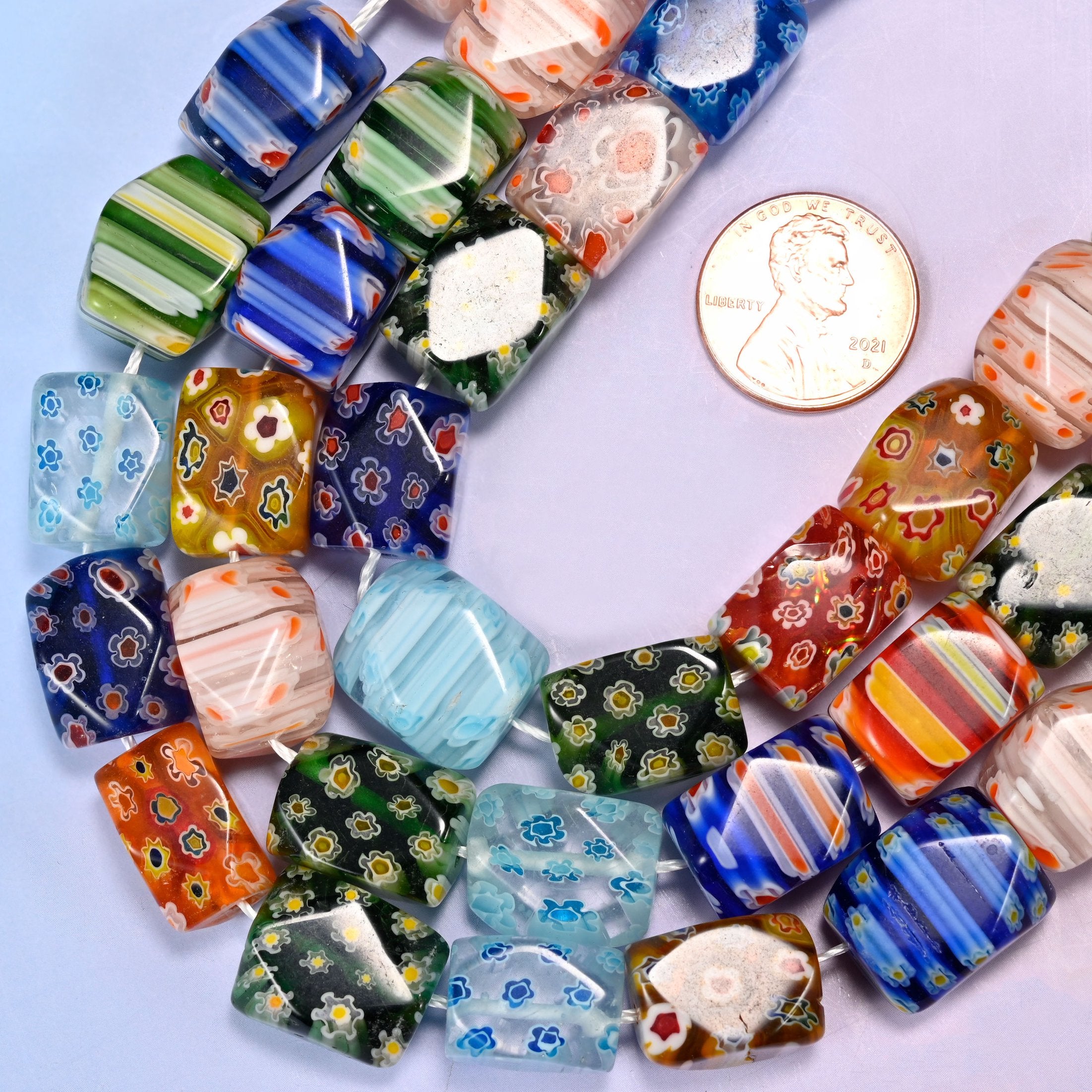 Faceted cuboid millefiori glass beads in cobalt, orange, green, sky blue, white and coral.