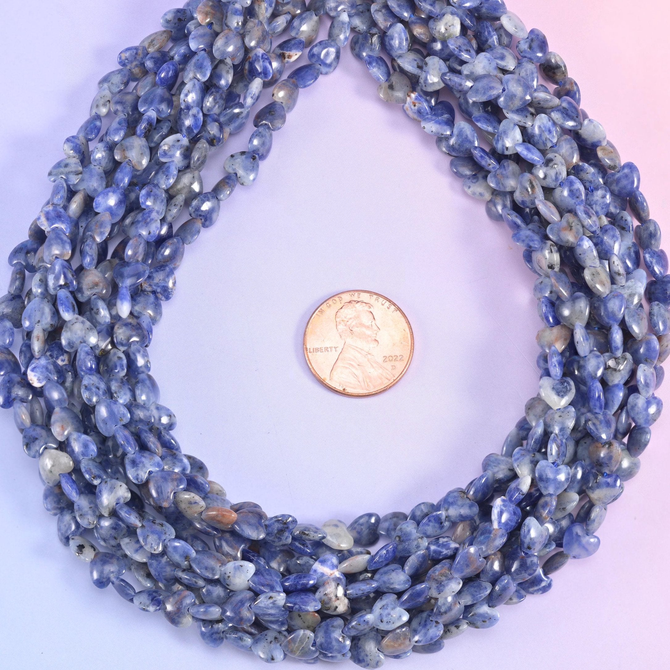 Tiny flat hearts in denim and royal blue marbled with chalk white and soft grey, a few carrying warm tan flecks, all polished smooth and rounded at the edges.