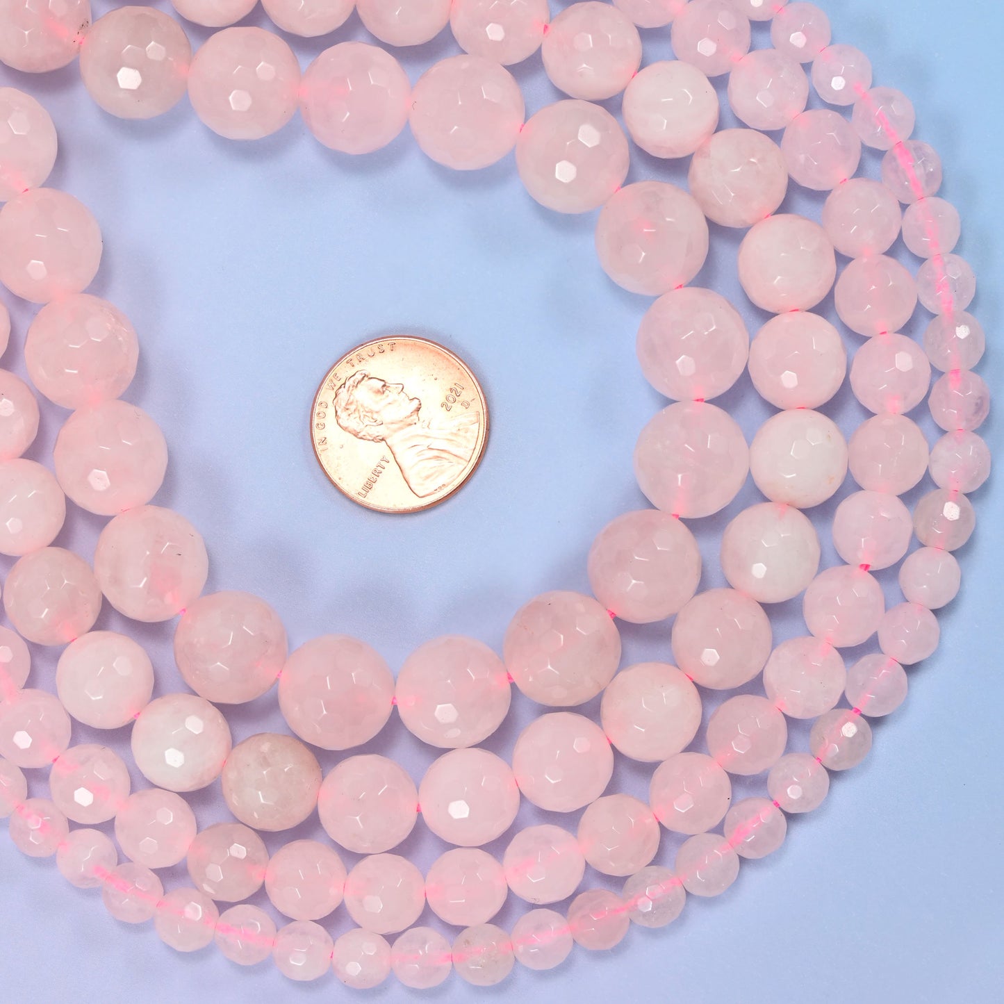 Group of pink rose quartz round beads showing natural color and pattern variation.