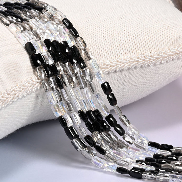 Black gray and clear faceted rectangle glass beads draped over a cream cushion, 7x4mm bars in a repeating black, gray and clear run