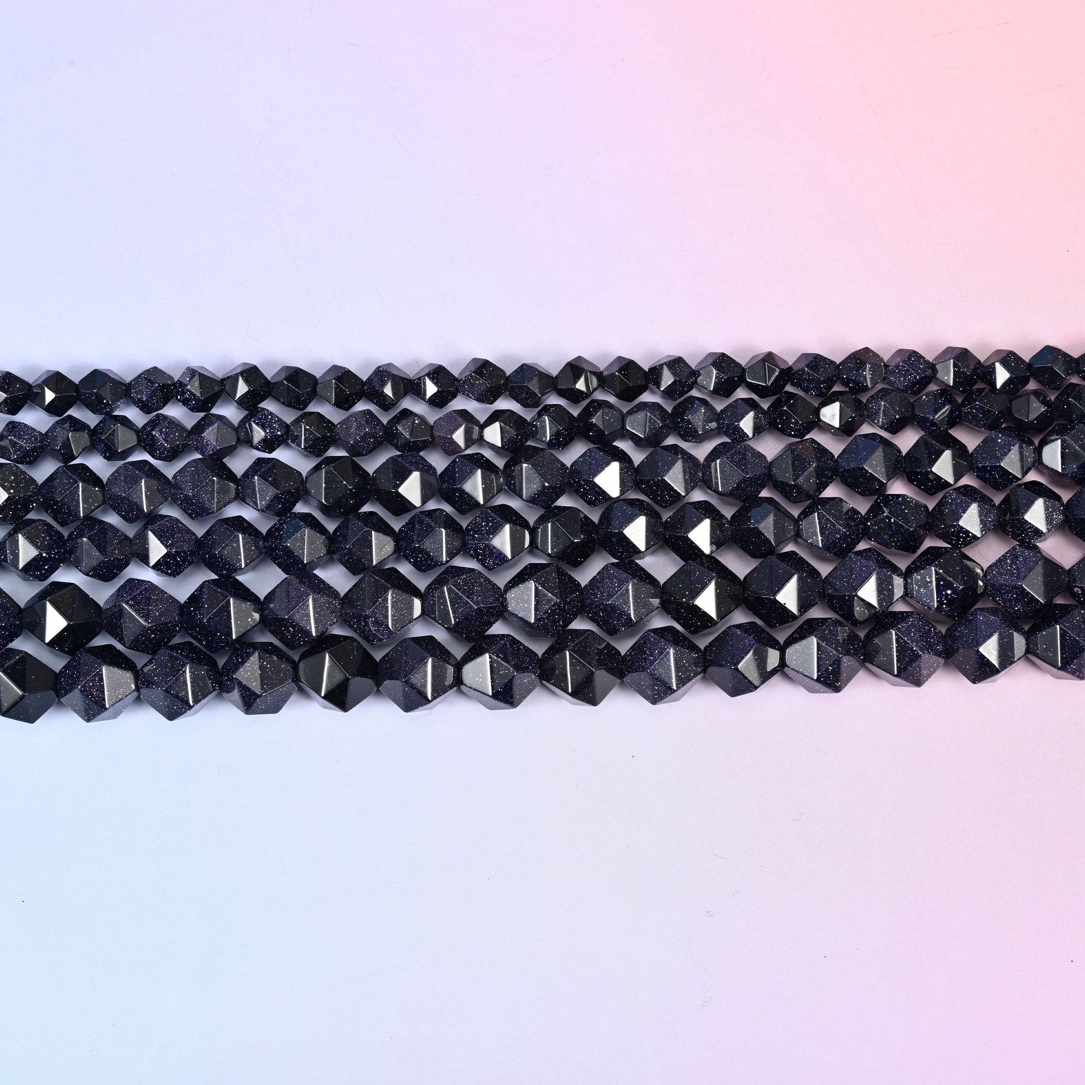 Straight rows of star cut blue sandstone beads laid flat, showing the even faceted points