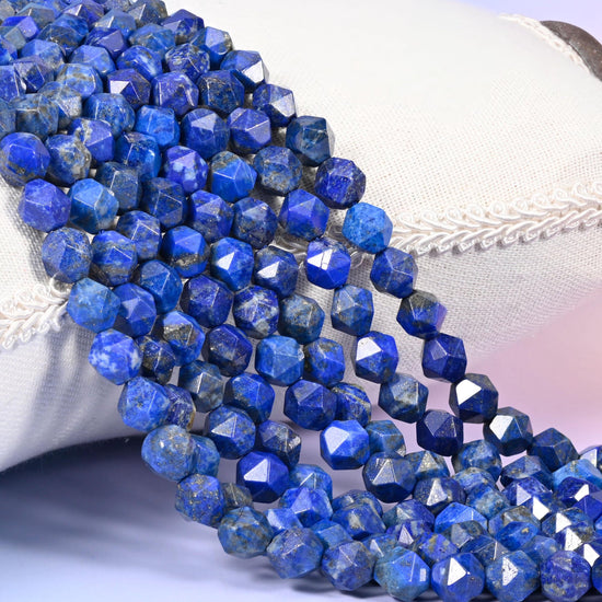 Blue Lapis Lazuli diamond star cut beads, strands draped over white fabric, royal blue stone marked with chalky white calcite veining