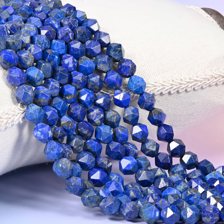 Blue Lapis Lazuli diamond star cut beads, strands draped over white fabric, royal blue stone marked with chalky white calcite veining