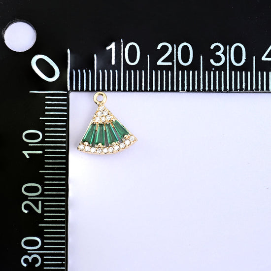 Small gold charms, one green fan charm at the corner of a millimetre ruler showing the size