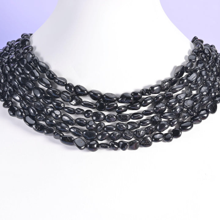 Black tourmaline pebble beads worn on a white bust as a multi-strand collar