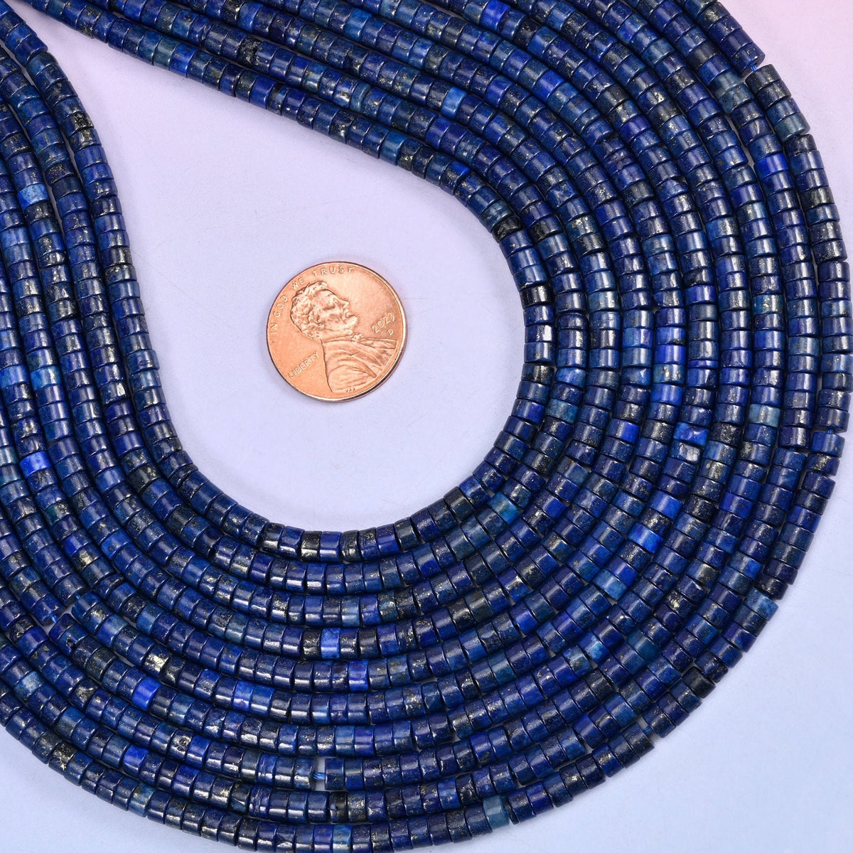 Natural Dark Blue Lapis Lazuli smooth heishi disc beads in deep royal blue with flecks of golden pyrite, finished with a polished, sophisticated look.
