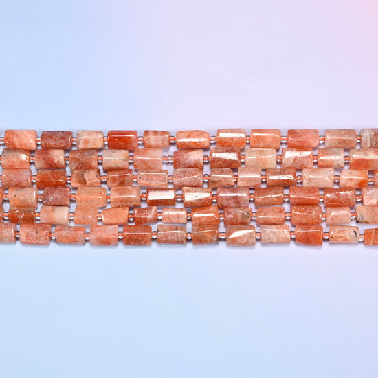 Close-up horizontal row of faceted Golden Strawberry Quartz tube beads with clear glass spacers, showing the golden orange stone pattern.