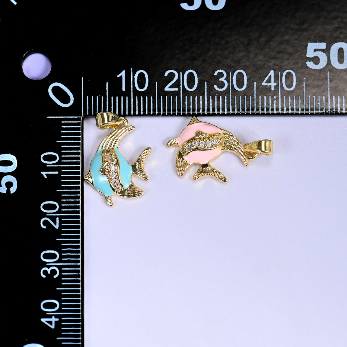 Turquoise and pink Enamel Tropical Fish Zirconia Charms on a black millimeter ruler, both colorways shown against the mm scale.