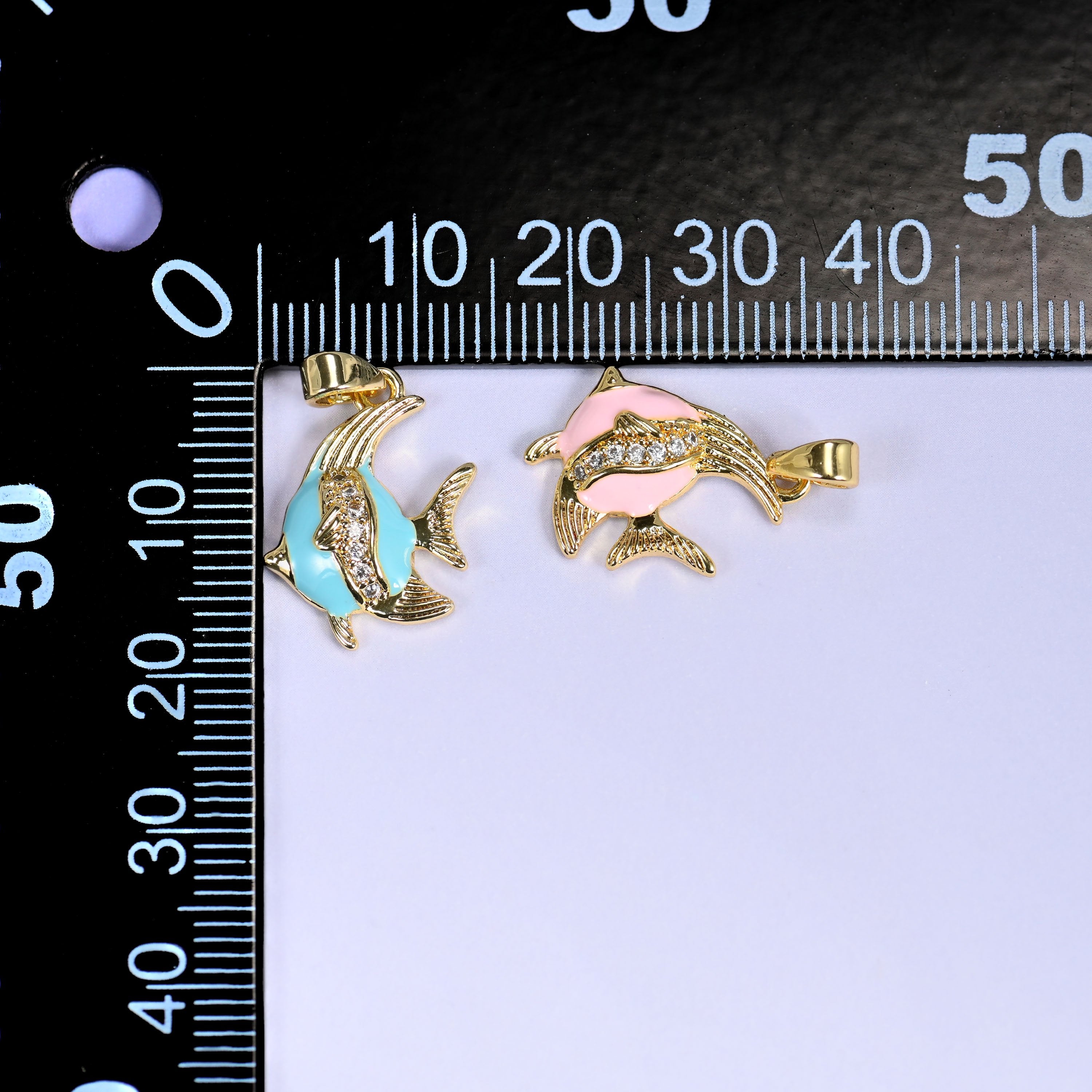 Turquoise and pink Enamel Tropical Fish Zirconia Charms on a black millimeter ruler, both colorways shown against the mm scale.
