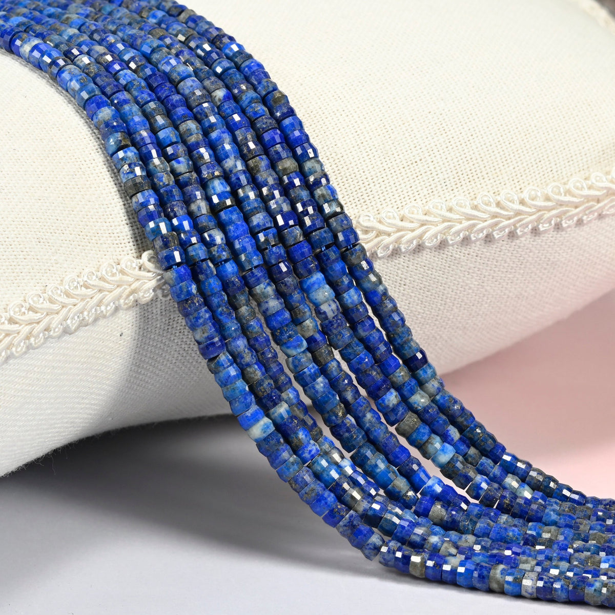 Lapis faceted heishi disc beads 2x4mm, several strands draped over a white cushion