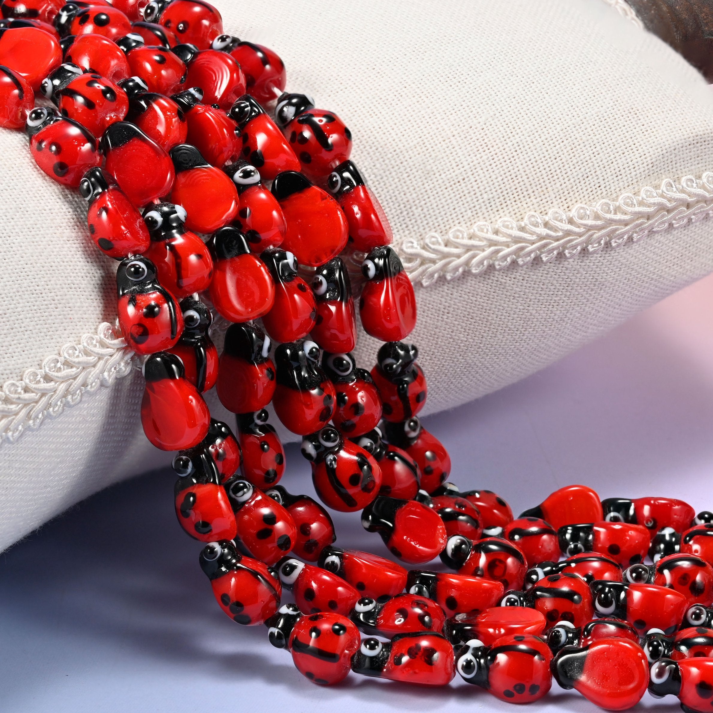 Red Ladybug Glass Beads, glossy scarlet oval beads painted with black spots and a black head.