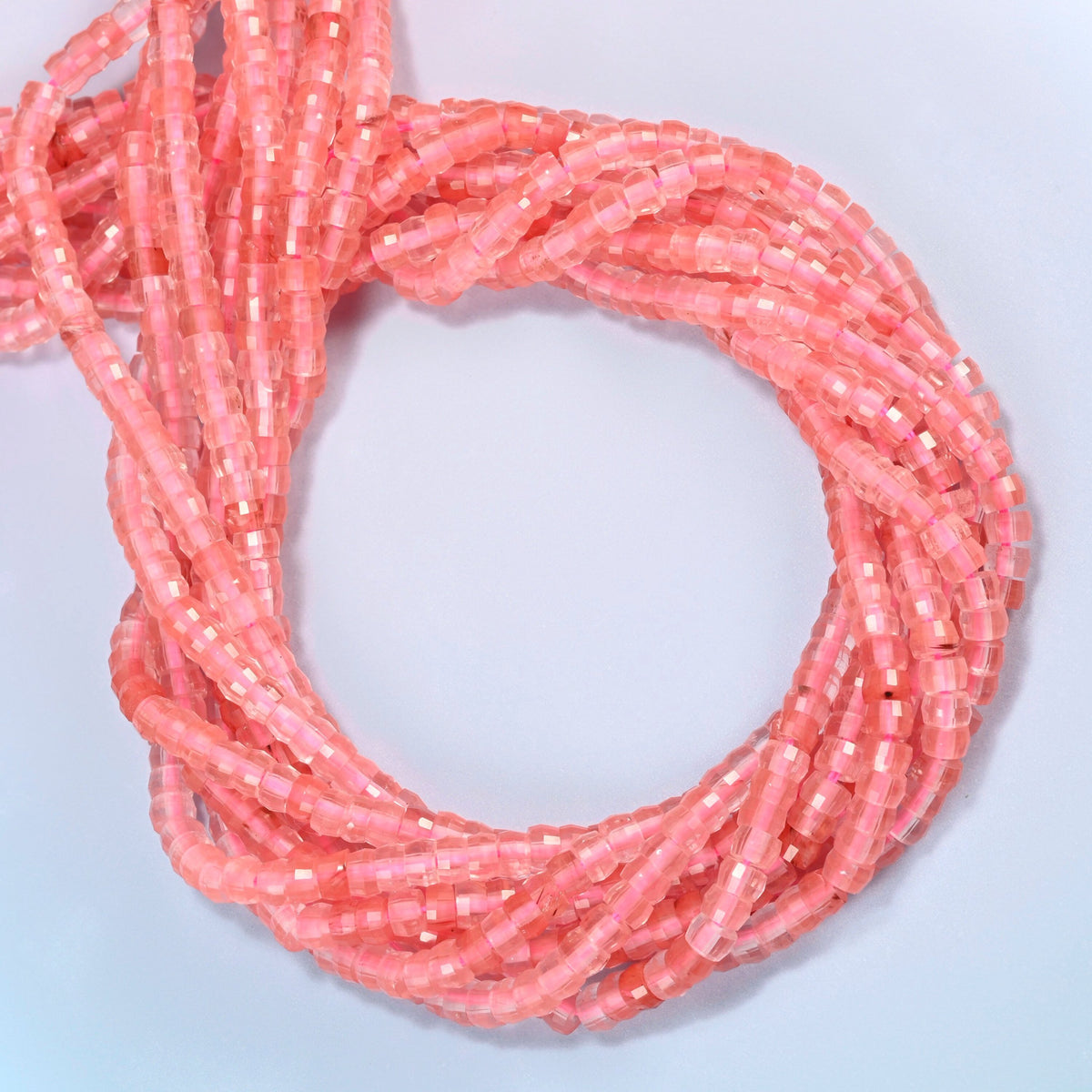 Melon quartz faceted heishi disc beads coiled into overlapping loops, whole strands of bright pink glass
