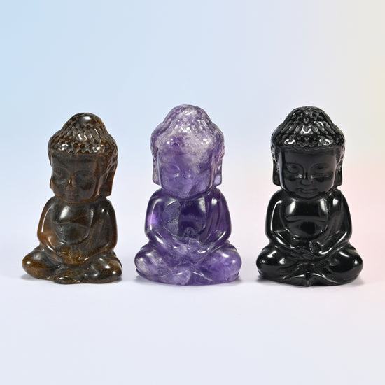 Three sitting Buddha carvings in natural tiger eye, amethyst and black obsidian, cross-legged in meditation