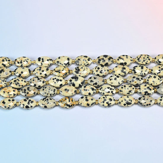 Several strands of dalmatian jasper faceted flat oval beads laid in straight rows with gold seed bead spacers