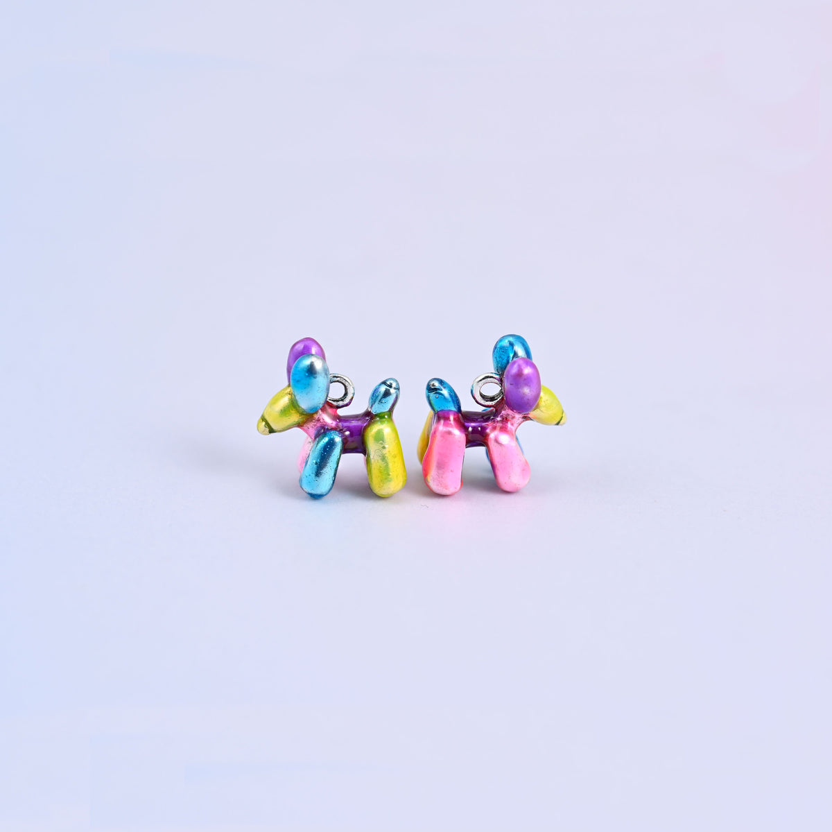 Balloon dog charms seen from the front, the twisted balloon body moulded in blue, purple, pink and yellow enamel.