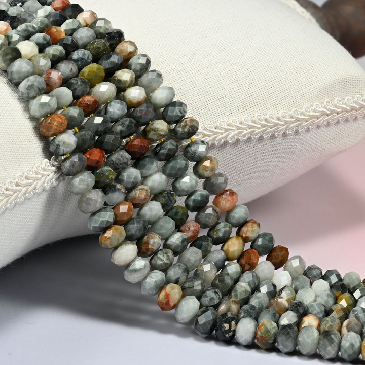 Eagle eye jasper faceted rondelle beads over a white cushion, gray green stone with orange beads.
