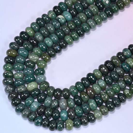 Circular coil of Moss Agate bead strands on a lavender background.
