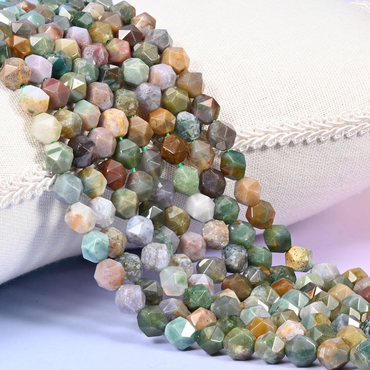 Indian Agate diamond star cut beads, strands laid over white fabric, mossy green and grey broken up by cream and rust beads