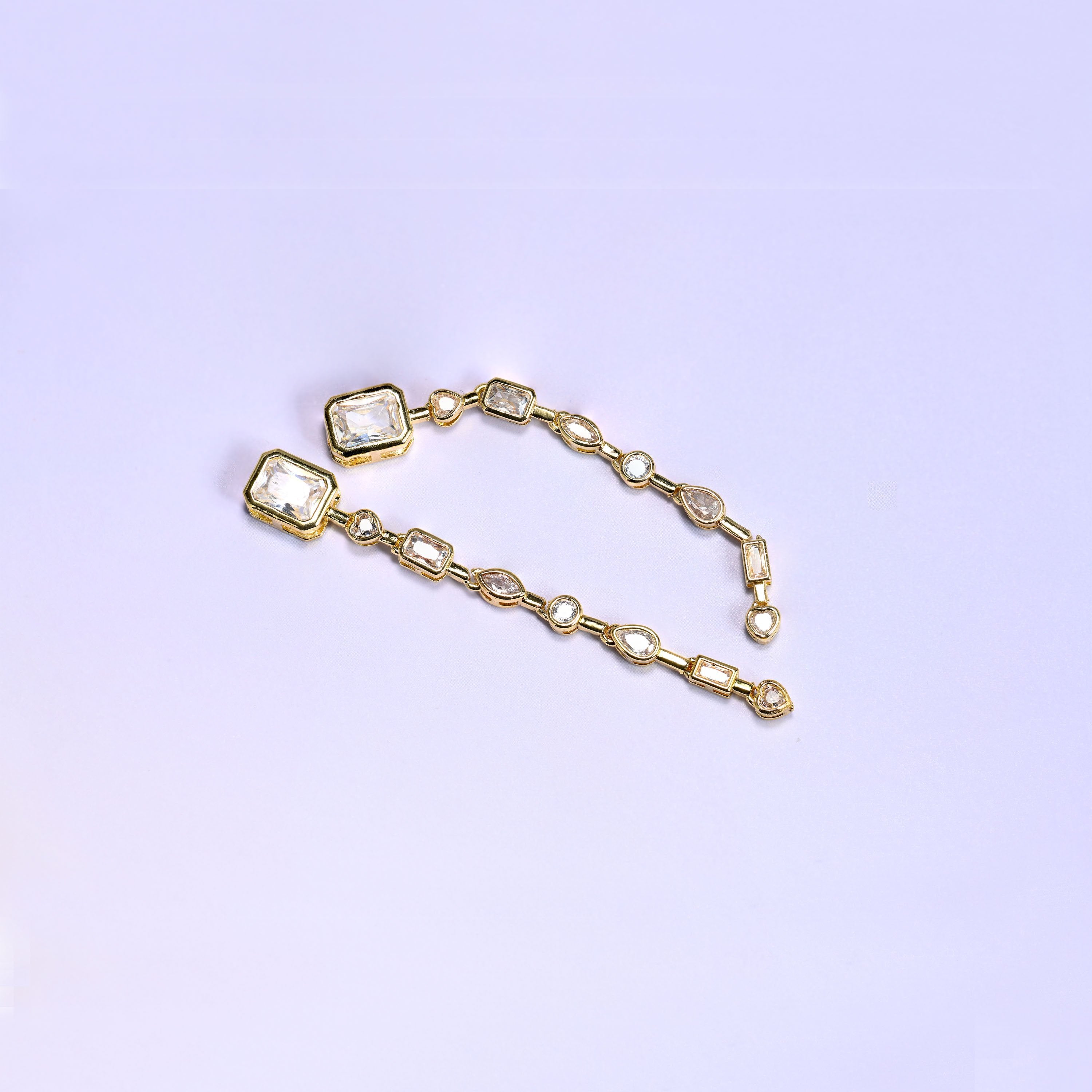 A run of clear zircon stones bezel-set in gold — rectangle, teardrop, oval and heart cuts in sequence, joined into one slim chain segment just under 68mm long