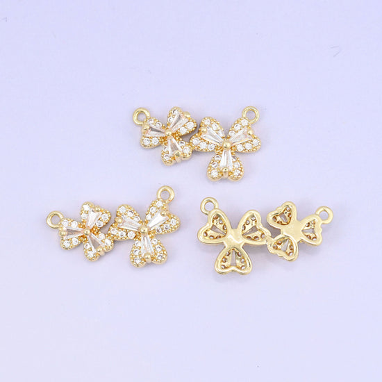 Three small flower blossoms set side by side, each petal pave set with clear zircon and outlined in warm gold