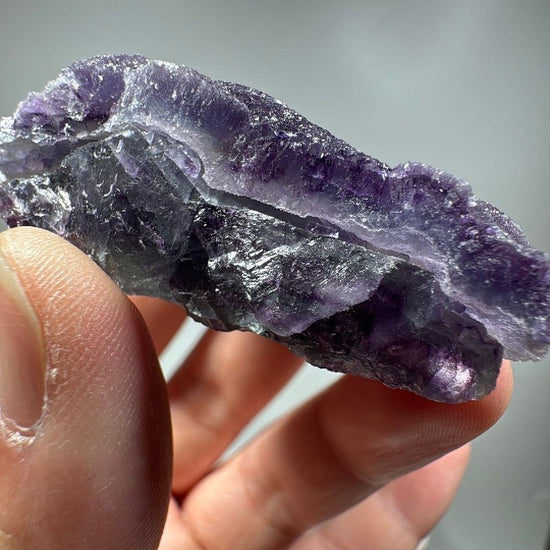 Side view of the fluorite piece showing layered violet and near-black banding through the stone