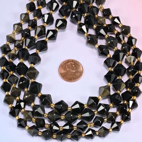 Gold obsidian bicone beads coiled into a ring, seen from above, gold sheen strongest on the upper facets.