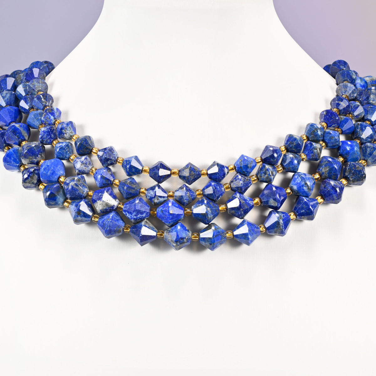 Lapis lazuli bicone beads curved into a collar, pale gray-white patches breaking up the blue on some beads.