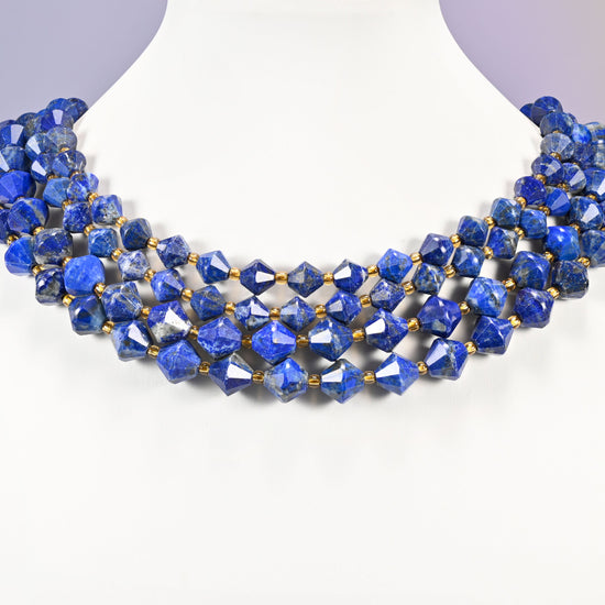 Lapis lazuli bicone beads curved into a collar, pale gray-white patches breaking up the blue on some beads.