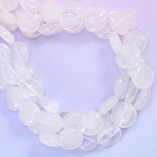 Open ring of clear quartz coins photographed from above, showing bead thickness and drill placement