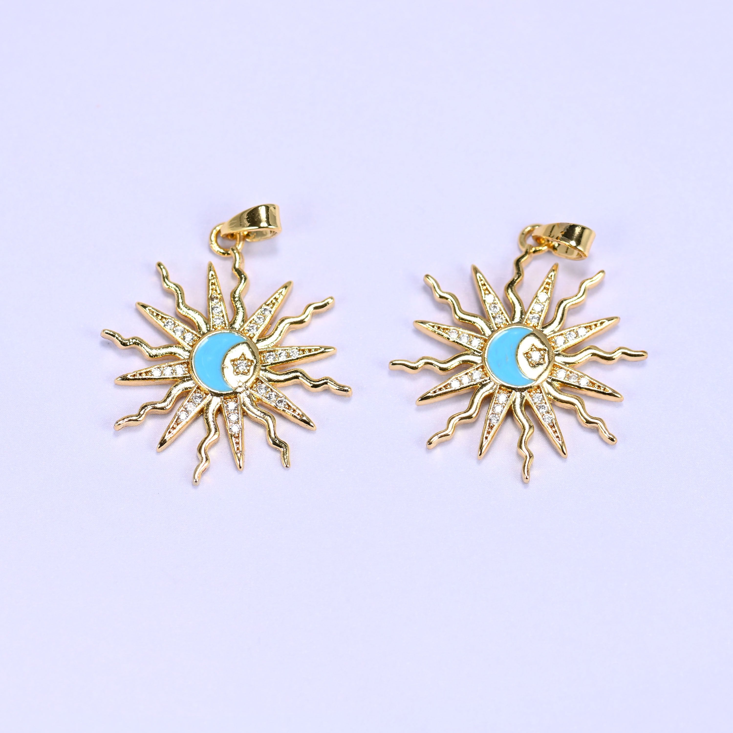 Enamel moon sun zirconia charms in blue, two gold sunburst pendants with pave rays circling a blue enamel crescent moon and star.