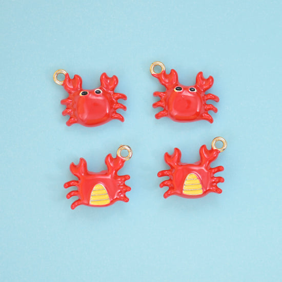 Enamel crab charms in red, front view with black eyes and reverse view showing the yellow striped belly