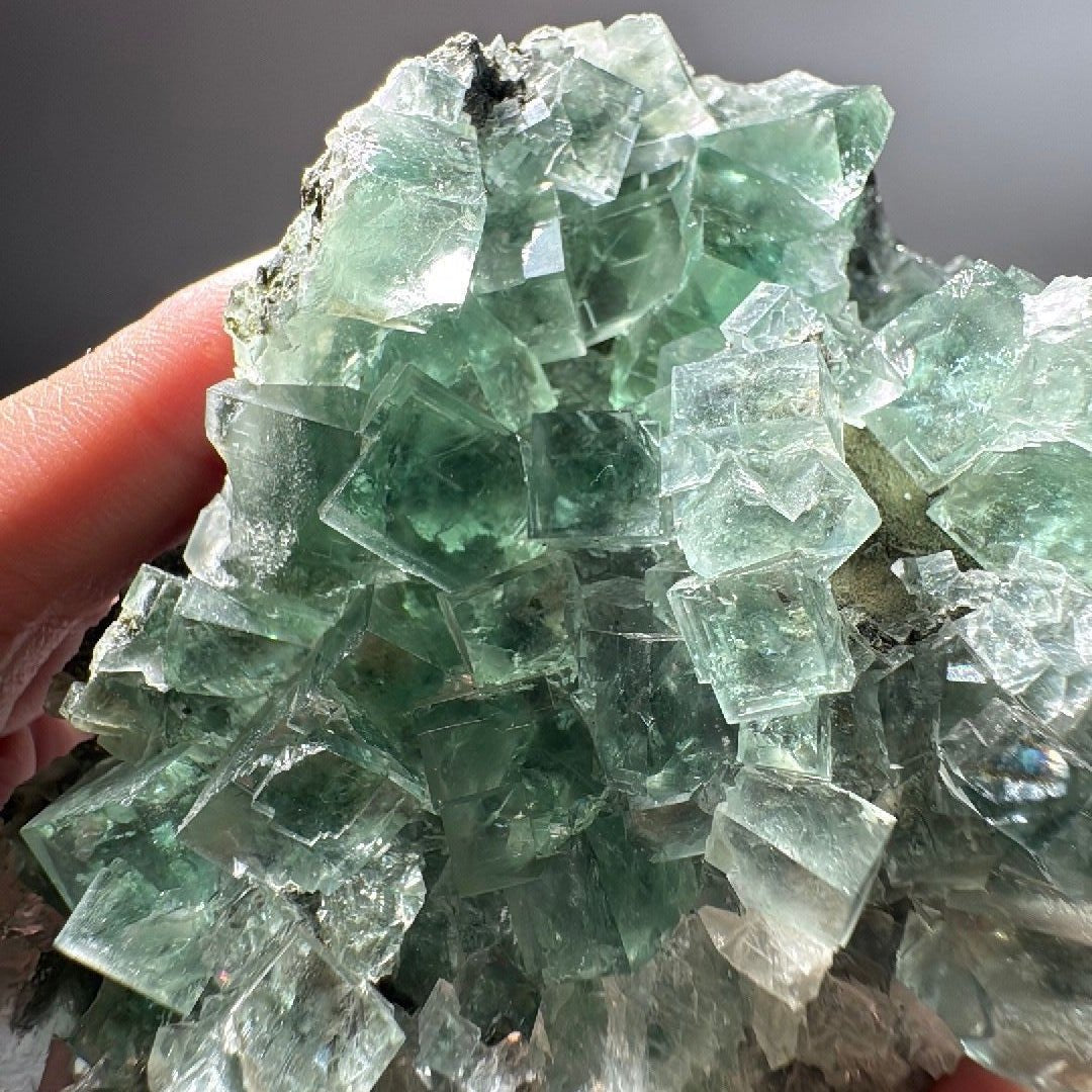 Hand-held green Fluorite cluster with deeper green cores in several cubes