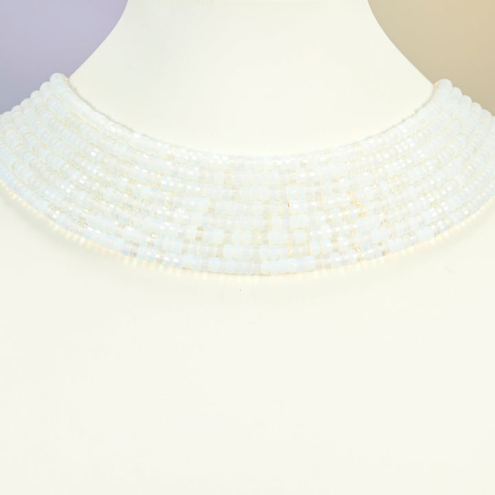 Opalite faceted heishi disc strands arranged as a layered collar on a white display bust, milky white beads across the neck