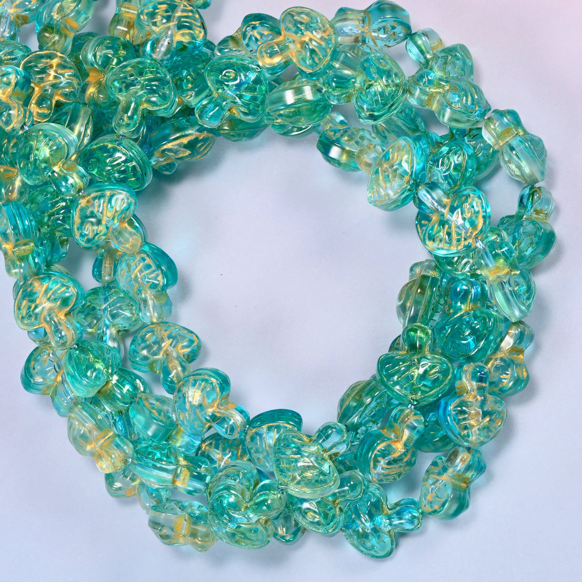 Aqua gold flat mushroom glass beads coiled into a densely packed ring with a small round opening.