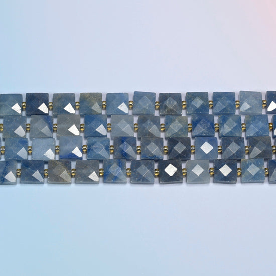Several strands of natural blue aventurine faceted flat square beads laid in straight rows