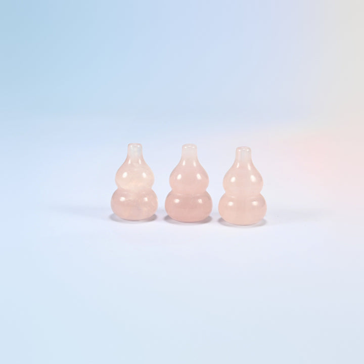Three 1.2 inch natural rose quartz gourd crystal carvings standing in a row, light pink